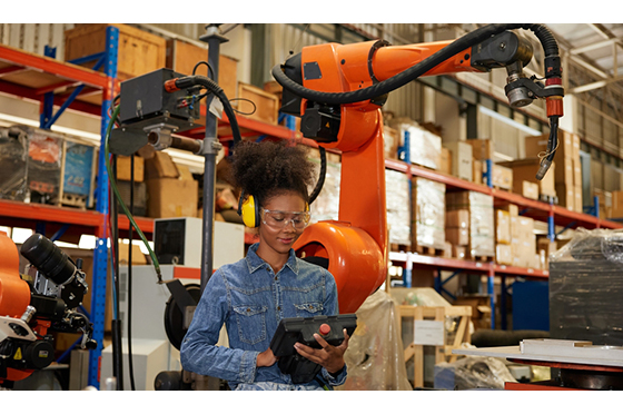 factory worker operating remote switch controller to control robot machine in the factory